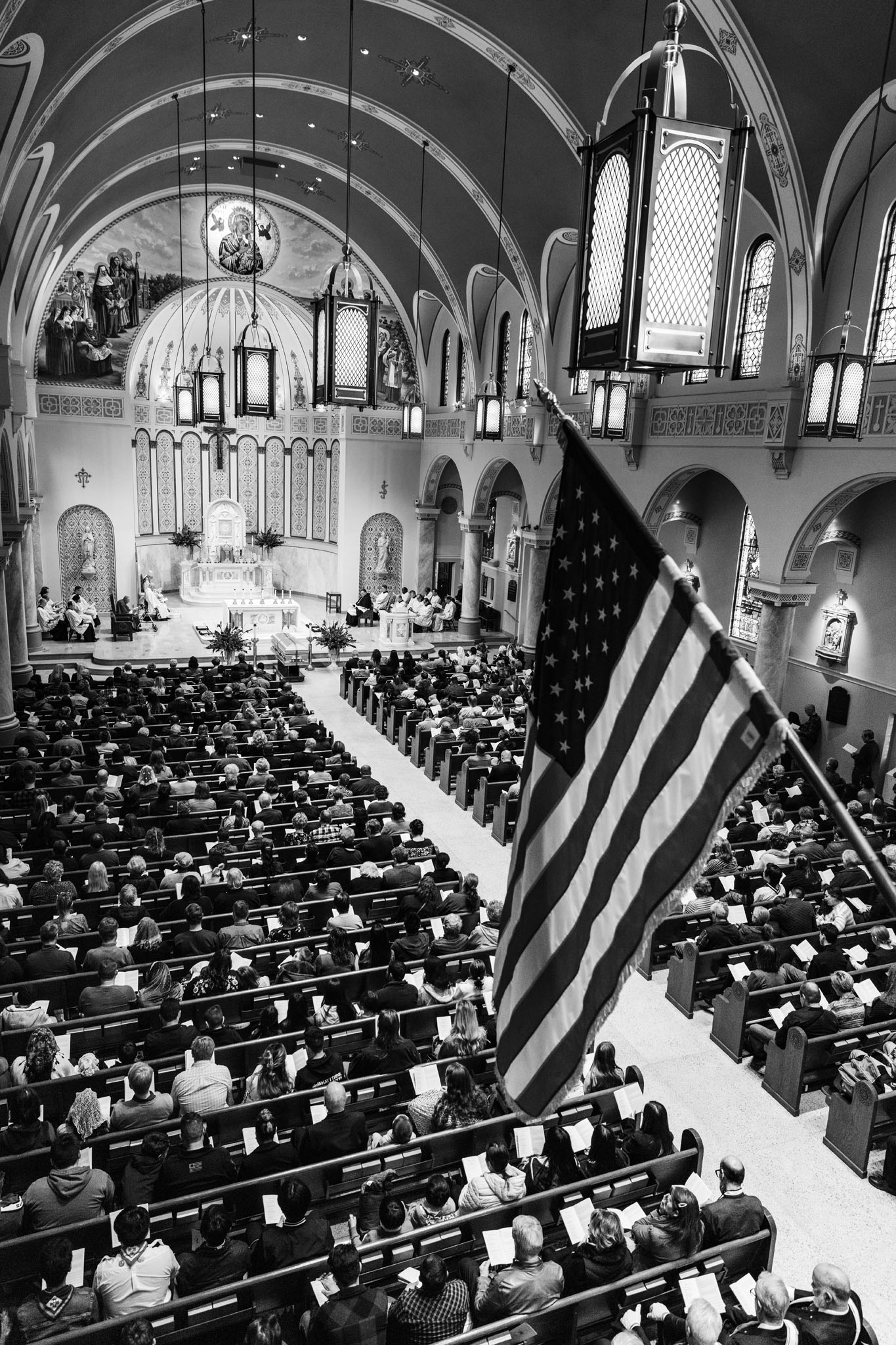 Packed pews and an American flag beneath the vaulted ceiling of the cathedral during the vigil