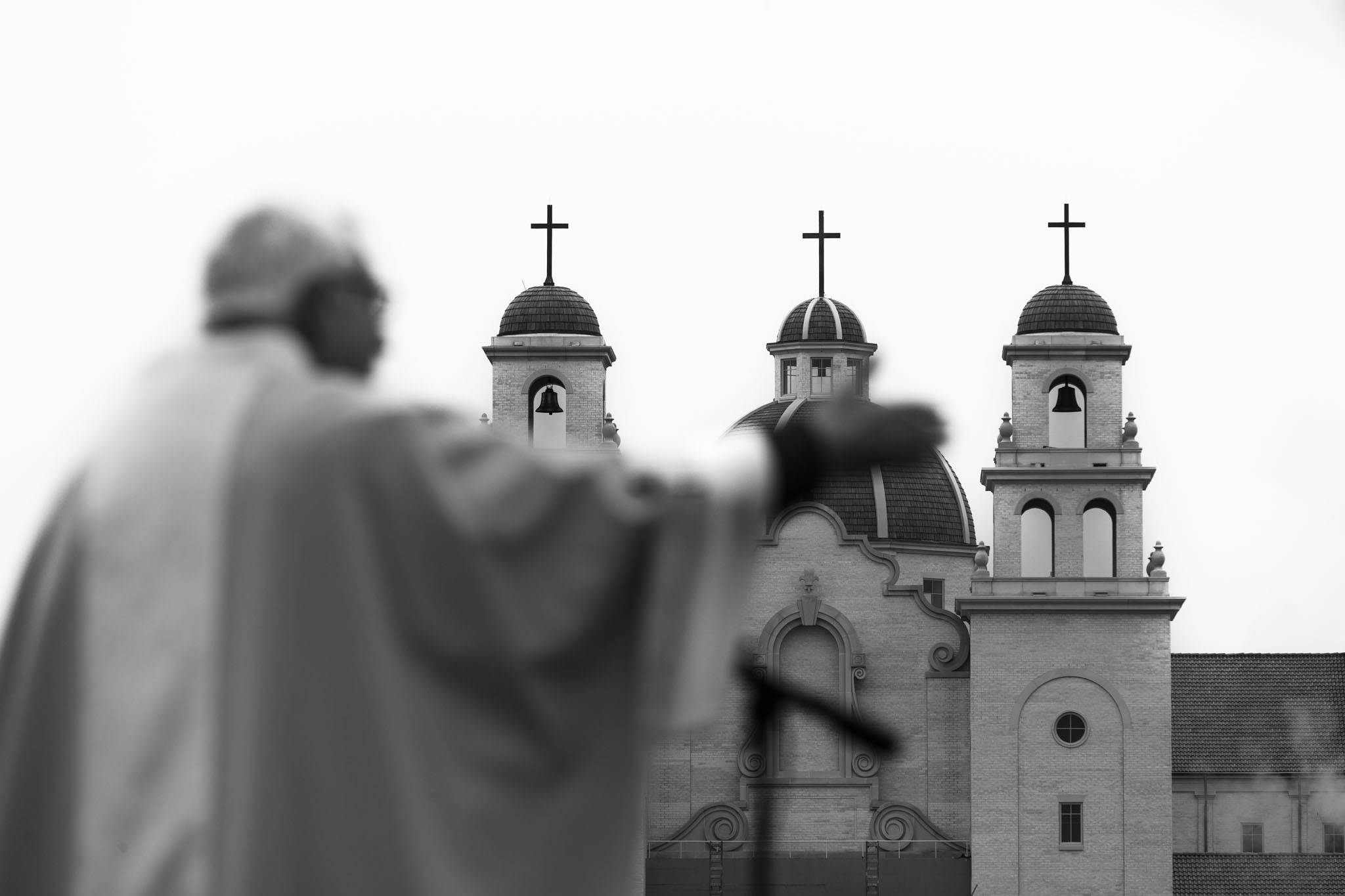 Bishop raising his hand in blessing in front of the shrine’s bell towers