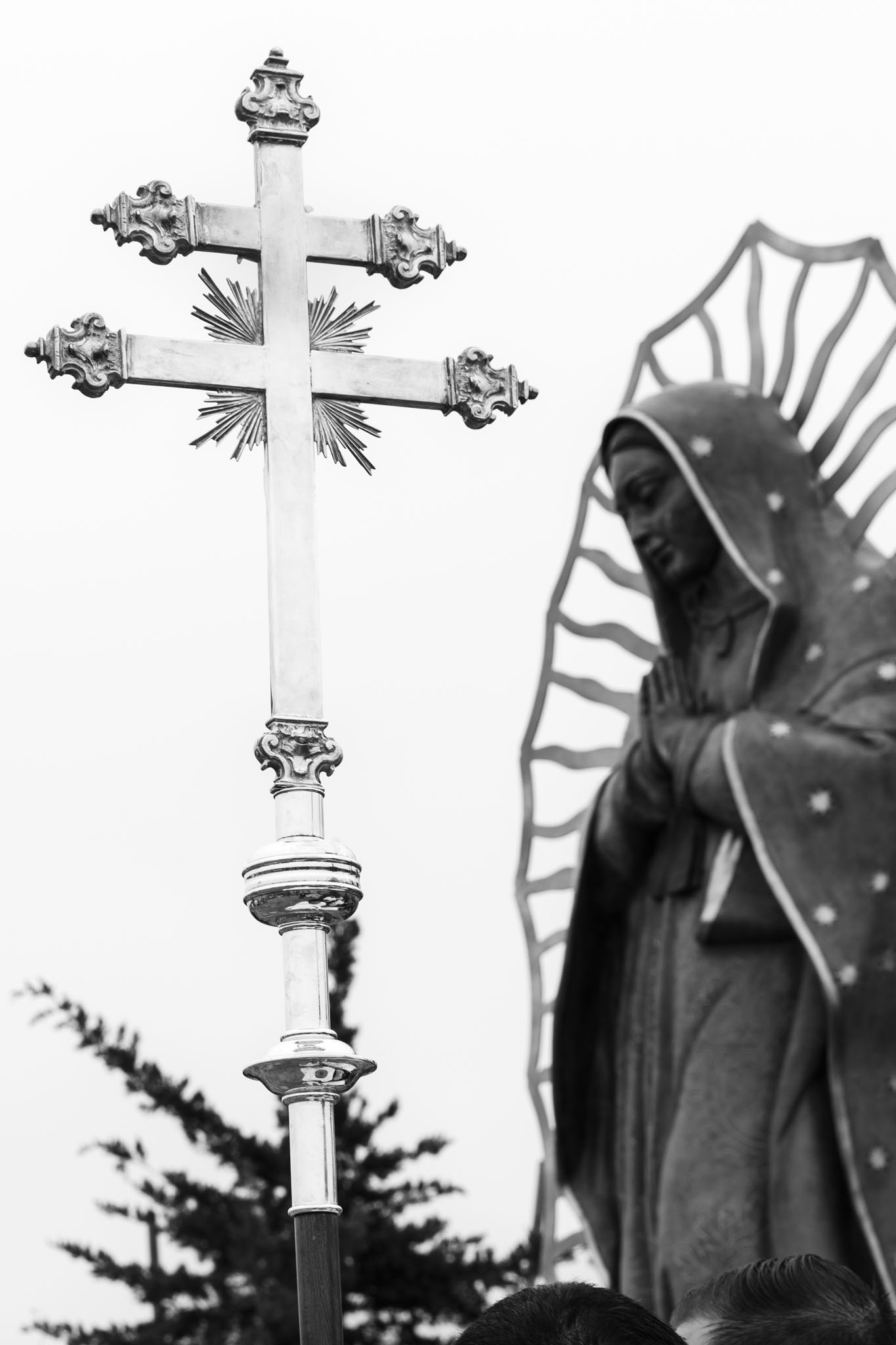 Processional cross raised beside a statue of Our Lady of Guadalupe