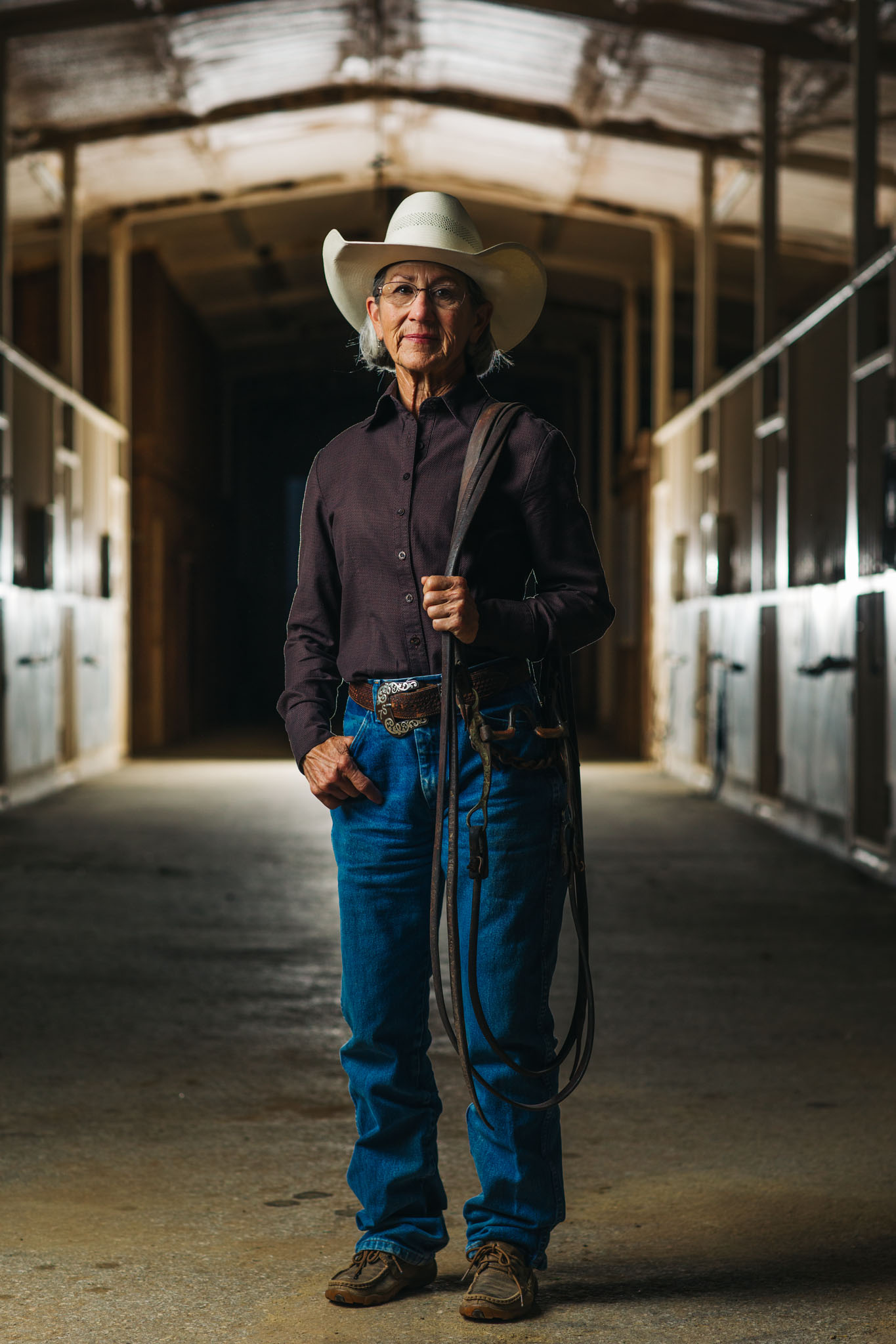Portrait of Terry Stuart Forst holding a rope in the aisle of her horse barn