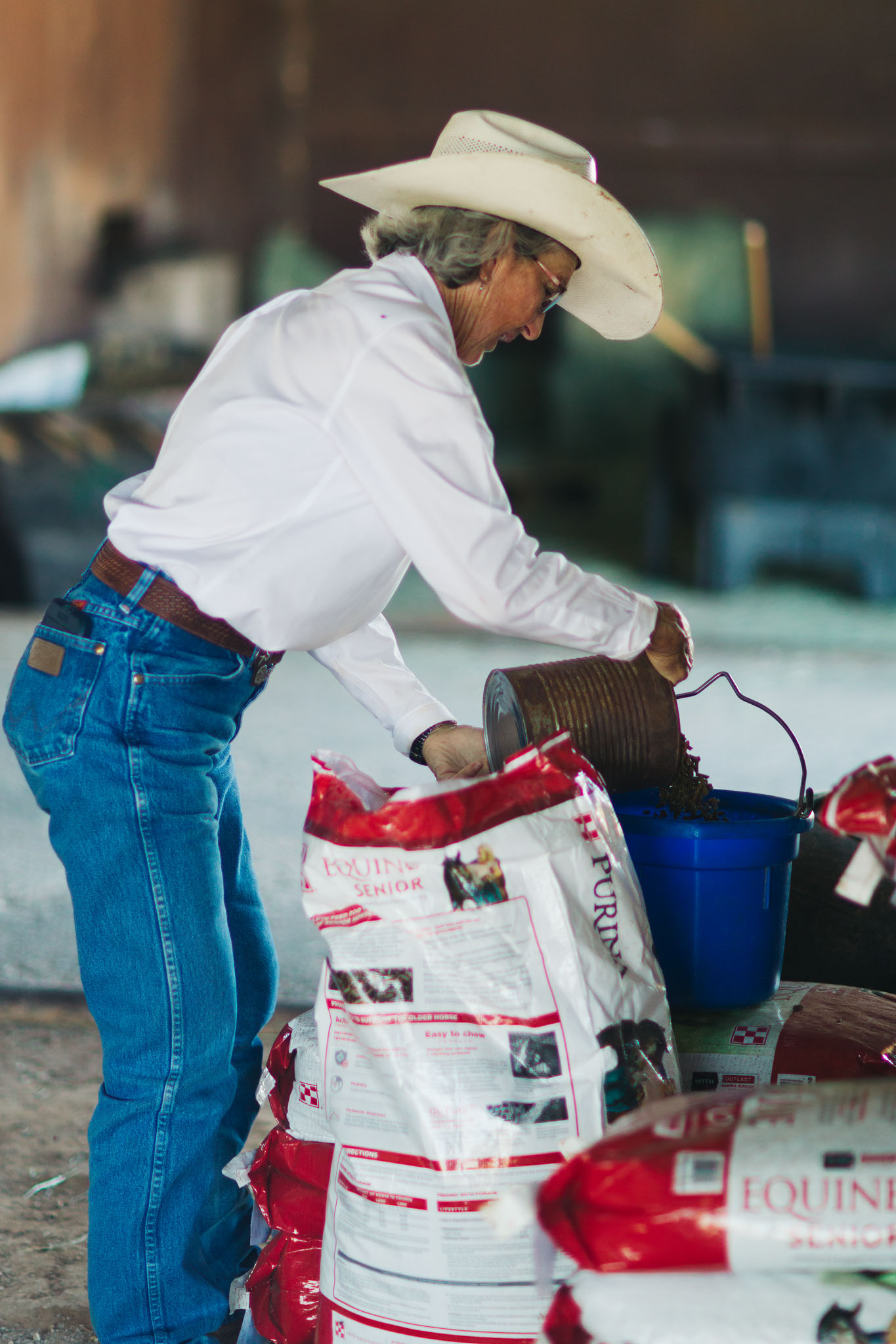 Terry Stuart Forst pouring feed into a bucket in the barn