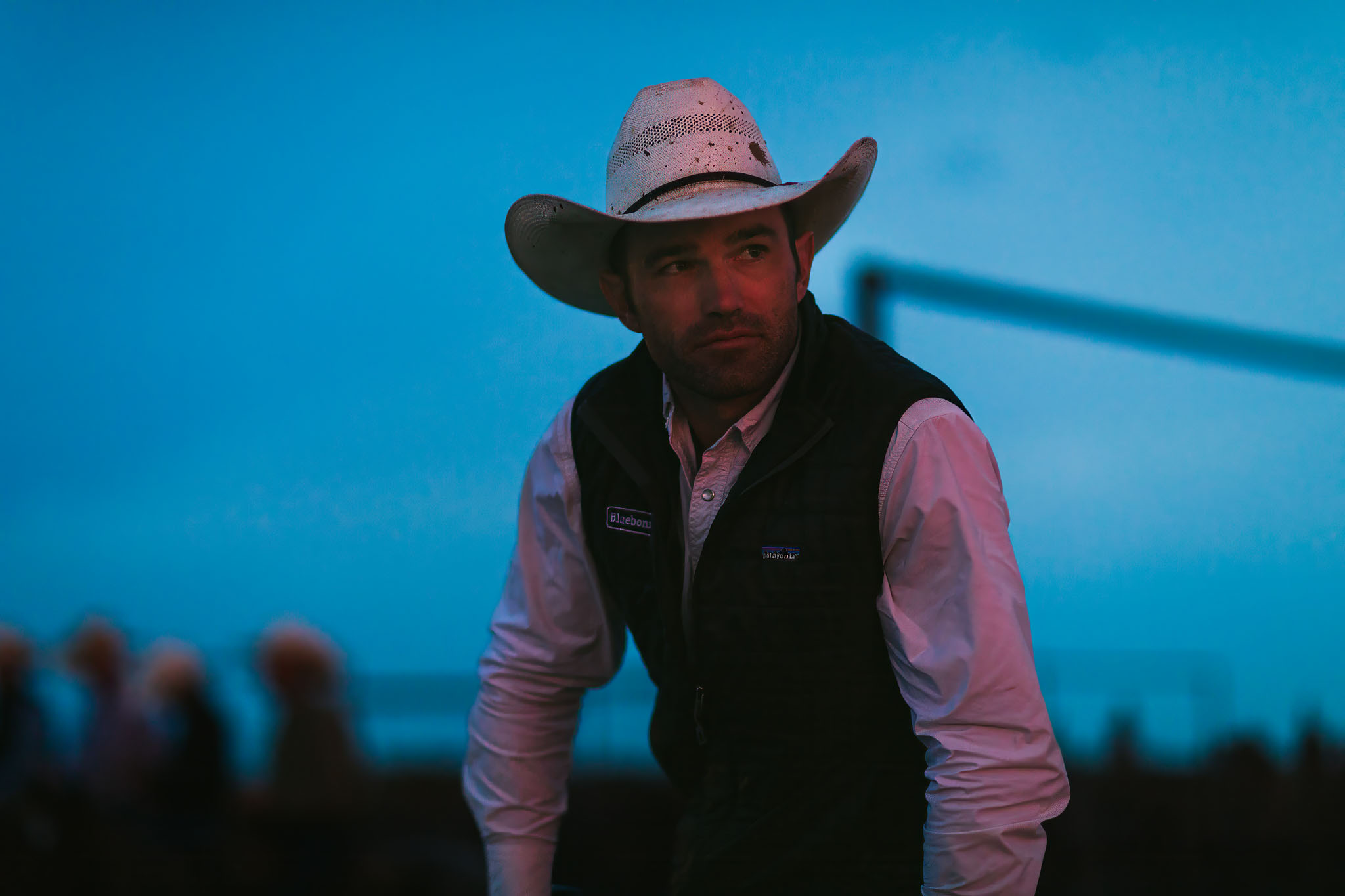 Cowboy in a white hat and black vest in the pens at blue hour